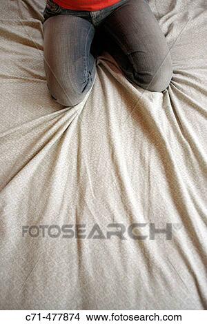 Picture - Woman's knees kneeling on the bed.. Fotosearch