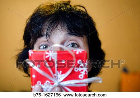 women 40 to 50 years showing a Christmas gift and covering part of the face View Large Photo Image Stock Photograph - women 40 to 50 years showing a Christmas gift and covering part of the face. Fotosearch