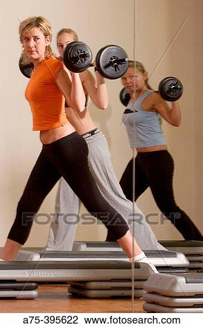 Stock Image - women doing weight lifting at the gym. Fotosearch