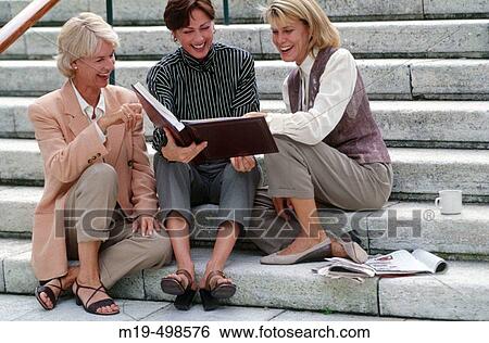 Stock Photograph - women looking at a picture album. Fotosearch