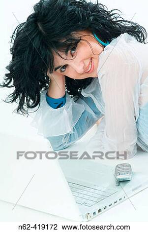 Women managers, winking and smiling, held his head lying in front of her laptop and mobile phone View Large Photo Image Stock Image - Women managers, winking and smiling, held his head lying in front of her laptop and mobile phone. Fotosearch