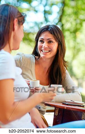 Picture - Women sisters 35 and 40 years taking coffee on a terrace. Donostia. San Sebastian. Gipuzkoa. Basque Country- Spain.. Fotosearch