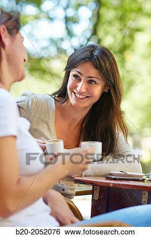 Stock Photograph - Women sisters 35 and 40 years taking coffee on a terrace. Donostia. San Sebastian. Gipuzkoa. Basque Country- Spain.. Fotosearch