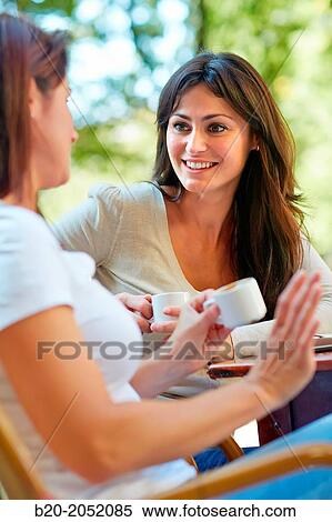 Stock Photography - Women sisters 35 and 40 years taking coffee on a terrace. Donostia. San Sebastian. Gipuzkoa. Basque Country- Spain.. Fotosearch