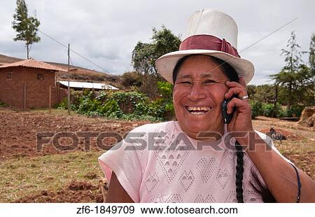Stock Photo - Wonderful farming woman on farm with cell phone in traditional dress and smiling happy workers in Chinchero Peru. Fotosearch