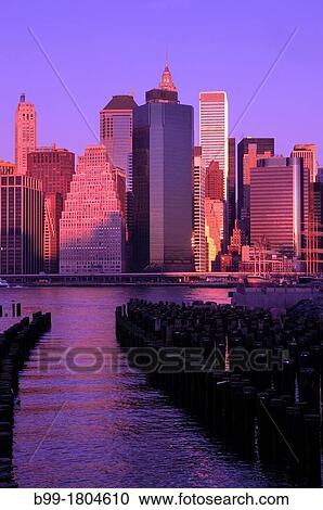 Stock Image - WOODEN PILINGS DOWNTOWN SKYLINE EAST RIVER MANHATTAN NEW YORK CITY USA. Fotosearch
