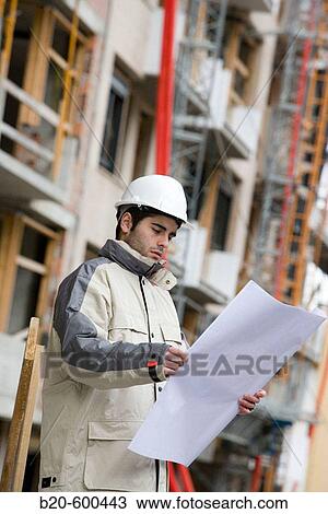 Stock Image - Worker and construction materials. Building construction.. Fotosearch