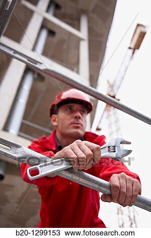 Worker holding adjustable spanner in a construction site View Large Photo Image Stock Image - Worker holding adjustable spanner in a construction site. Fotosearch