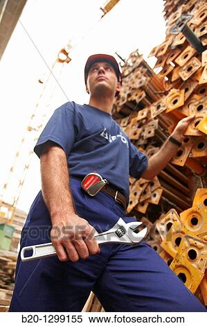 Worker holding adjustable spanner in a construction site View Large Photo Image Stock Photography - Worker holding adjustable spanner in a construction site. Fotosearch