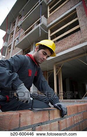 Worker making brick wall with trowel. Building construction. View Large Photo Image Stock Photograph - Worker making brick wall with trowel. Building construction.. Fotosearch