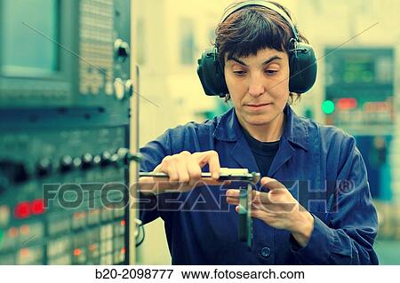 Stock Photo - Worker measuring with caliper. Area automated CNC lathes. Machined Indecober. Machining of precision parts in series. Automotive industry. Berriz. Bizkaia. Basque Country. Spain.. Fotosearch
