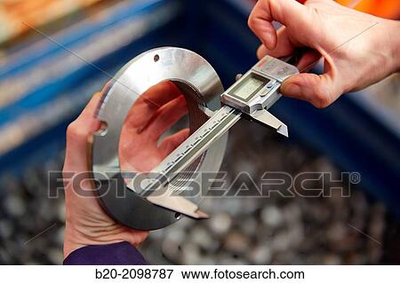 Stock Photo - Worker measuring with caliper. Area automated CNC lathes. Machined Indecober. Machining of precision parts in series. Automotive industry. Berriz. Bizkaia. Basque Country. Spain.. Fotosearch