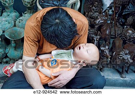 Worker resting with his baby on arms, Pan Jia Yuan flea market, Beijing, China View Large Photo Image Stock Image - Worker resting with his baby on arms, Pan Jia Yuan flea market, Beijing, China. Fotosearch