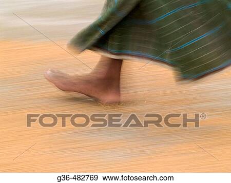 Worker uses his feet as he turns over rice that is drying in a rice processing center on a farm in rural Bangladesh View Large Photo Image Stock Photo - Worker uses his feet as he turns over rice that is drying in a rice processing center on a farm in rural Bangladesh. Fotosearch