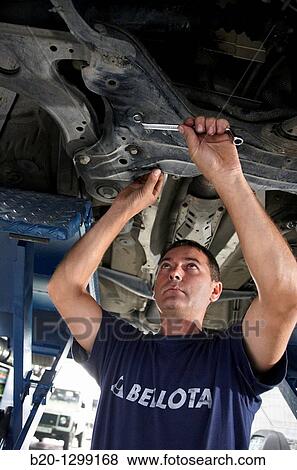 Stock Photo - Worker using ring spanner in car repair shop. Fotosearch