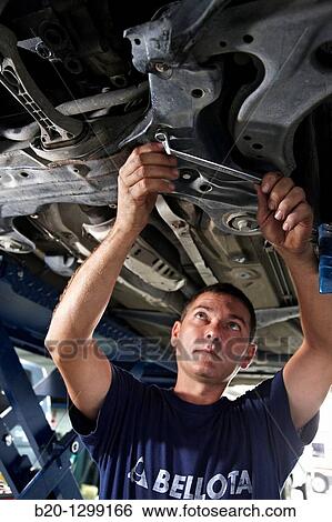 Stock Photograph - Worker using ring spanner in car repair shop. Fotosearch