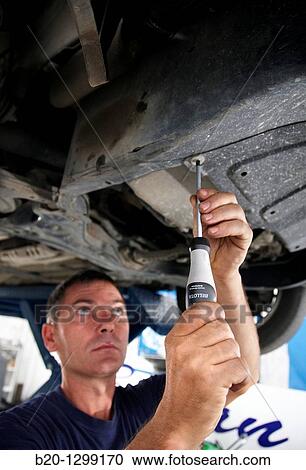 Worker using screwdriver in car repair shop View Large Photo Image Stock Image - Worker using screwdriver in car repair shop. Fotosearch