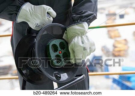 Worker with an electrical wire extension and protective gloves. View Large Photo Image Picture - Worker with an electrical wire extension and protective gloves.. Fotosearch