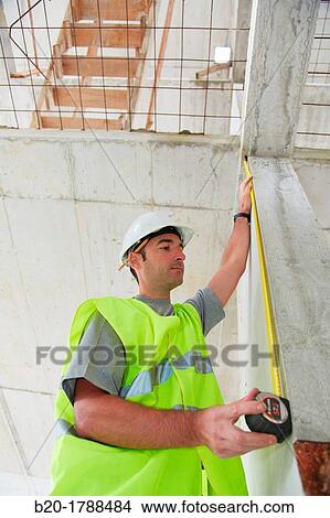 Picture - Worker with protective equipment, PPE, Taking measures in concrete beam, retractable tape, housing construction, Basque Country, Spain. Fotosearch