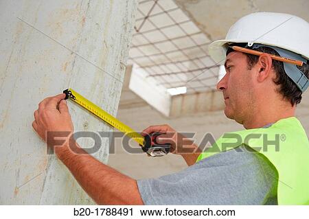 Stock Image - Worker with protective equipment, PPE, Taking measures in concrete beam, retractable tape, housing construction, Basque Country, Spain. Fotosearch
