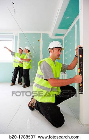 Stock Photo - Worker with protective equipment, PPE, Leveling plasterboard panels, housing construction, level, Basque Country, Spain. Fotosearch