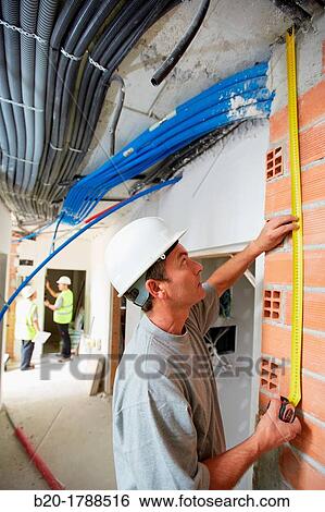 Worker with protective equipment, PPE, Taking retractable tape measures, housing construction, brick wall, Basque Country, Spain View Large Photo Image Stock Photograph - Worker with protective equipment, PPE, Taking retractable tape measures, housing construction, brick wall, Basque Country, Spain. Fotosearch
