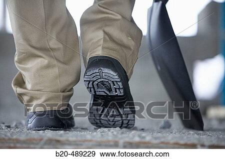 Worker with shovel and safety footwear. Housing construction, apartments. San Sebastian, Gipuzkoa, Euskadi. Spain. View Large Photo Image Stock Photo - Worker with shovel and safety footwear. Housing construction, apartments. San Sebastian, Gipuzkoa, Euskadi. Spain.. Fotosearch