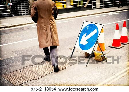 Works signs on the street and an unrecognizable man crossing. London, England, UK, Europe. View Large Photo Image Picture - Works signs on the street and an unrecognizable man crossing. London, England, UK, Europe.. Fotosearch