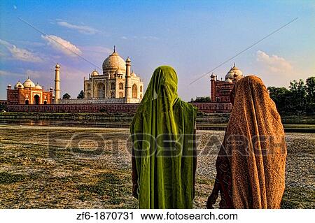World famous Taj Mahal temple burial site at sunset with women in sari from Yamuna River with reflection in town of Agra India View Large Photo Image Stock Image - World famous Taj Mahal temple burial site at sunset with women in sari from Yamuna River with reflection in town of Agra India. Fotosearch