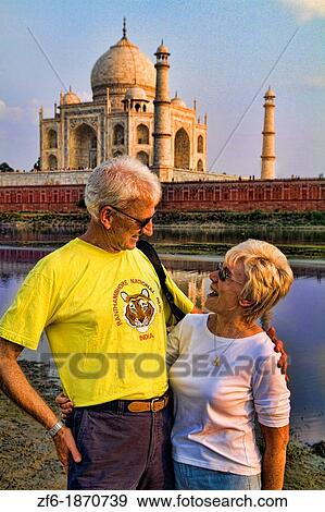 World famous Taj Mahal temple with romantic retired holiday couple at sunset from Yamuna River with reflection in town of Agra India View Large Photo Image Stock Photo - World famous Taj Mahal temple with romantic retired holiday couple at sunset from Yamuna River with reflection in town of Agra India. Fotosearch