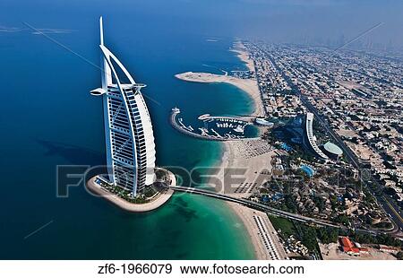 Stock Photo - Worlds only 7 star hotel in Dubai UAE called the Burj Al Arab from helicopter above aerial with luxury and water at beach in United Arab Emirates.. Fotosearch