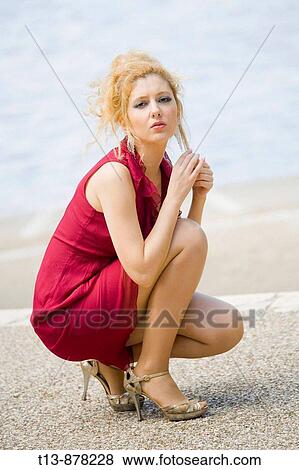 Stock Photo - Worried fancy young woman is squatting outdoors. Fotosearch
