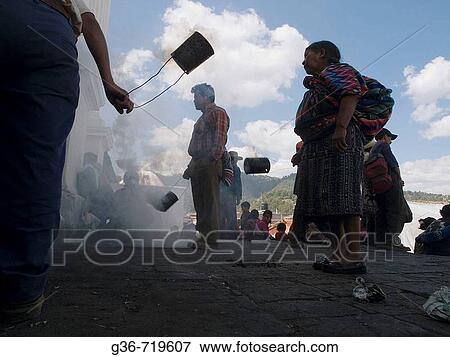 Stock Photo - Worshippers swinging incense burning in cans outsiude church in Chichicastenango, Guatemala. Fotosearch
