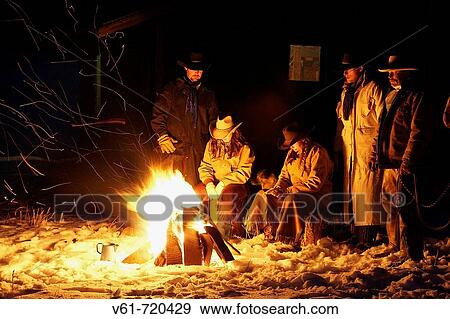 Stock Photo - Wranglers gathered by the evening fire in the snow, Shell, Wyoming. Usa. Fotosearch