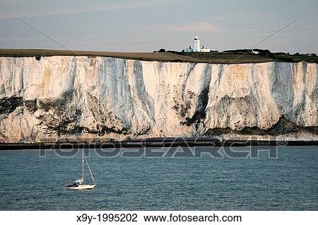Yacht passing along the White cliffs of Dover in the English Channel east of Dover below South Foreland lighthouse. Dawn light. View Large Photo Image Stock Image - Yacht passing along the White cliffs of Dover in the English Channel east of Dover below South Foreland lighthouse. Dawn light.. Fotosearch