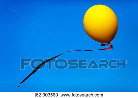 Yellow balloon with red ribbon flying in the blue sky View Large Photo Image Stock Image - Yellow balloon with red ribbon flying in the blue sky. Fotosearch