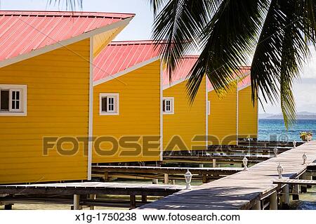 Stock Photo - Yellow waterfront cabins at El Faro del Colibri hotel on Isla Carenero, Bocas del Toro Archipelago, Panama. Fotosearch