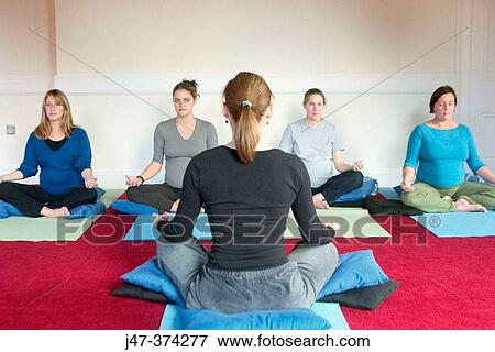 Yoga teacher sitting cross legged in front of class of four pre-natal women View Large Photo Image Stock Photo - Yoga teacher sitting cross legged in front of class of four pre-natal women. Fotosearch