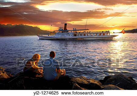 Youg couple watching a ferry at sunset on Lac Leman lake Geneva - Montraux Switzerland View Large Photo Image Stock Photography - Youg couple watching a ferry at sunset on Lac Leman lake Geneva - Montraux Switzerland. Fotosearch