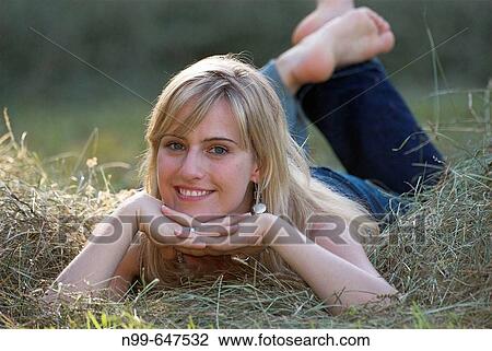 Youg woman lying in hay, looking to the camera, summertime, being outdoor, good mood View Large Photo Image Stock Image - Youg woman lying in hay, looking to the camera, summertime, being outdoor, good mood. Fotosearch
