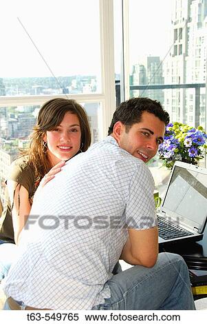 Stock Photography - young adult couple at home using laptop computer. Fotosearch