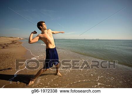 Stock Photo - Young adult doing workout at the Saler beach, Valencia, Spain. Fotosearch