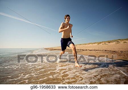 Stock Image - Young adult running at the beach.. Fotosearch