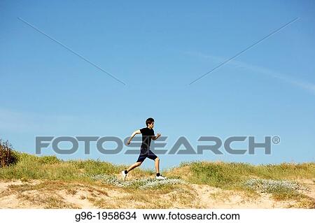 Young adult running in the dunes. View Large Photo Image Picture - Young adult running in the dunes.. Fotosearch