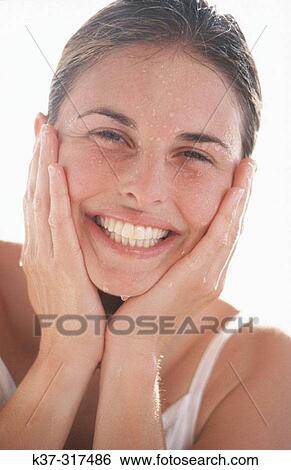 Young adult woman with clear skin splashing water on her face View Large Photo Image Stock Photograph - Young adult woman with clear skin splashing water on her face. Fotosearch