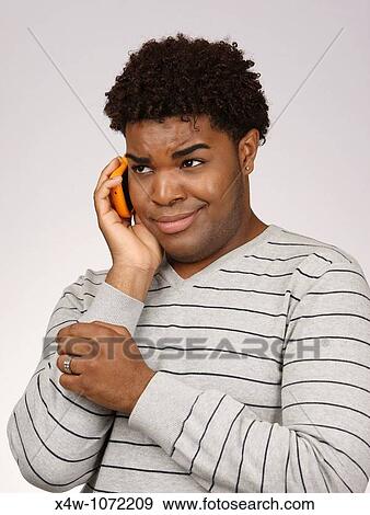 Young African-American man talking on cell phone View Large Photo Image Stock Photo - Young African-American man talking on cell phone. Fotosearch