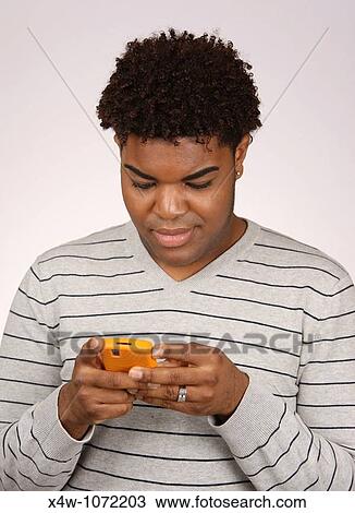 Stock Image - Young African-American man texting. Fotosearch