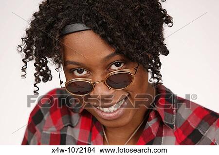 Young African-American woman looking over sunglasses posing for portrait View Large Photo Image Picture - Young African-American woman looking over sunglasses posing for portrait. Fotosearch
