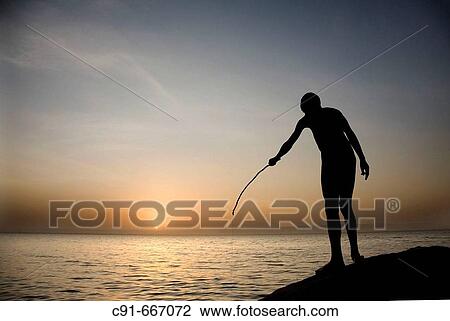 Stock Image - Young African man fishing at sunset. South Ethiopia. African people. Fotosearch