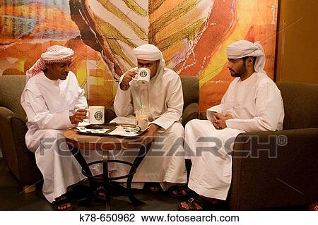 Young arab men with traditional dress sitting at starbucks cafe in Deira city centre shopping mall. Dubai, United Arab Emirates. View Large Photo Image Stock Image - Young arab men with traditional dress sitting at starbucks cafe in Deira city centre shopping mall. Dubai, United Arab Emirates.. Fotosearch